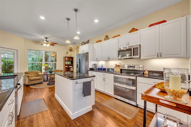 kitchen with white cabinetry, light hardwood / wood-style flooring, stainless steel appliances, and hanging light fixtures