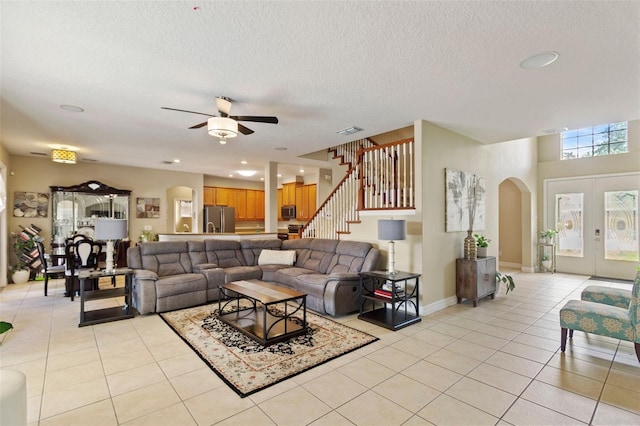 tiled living room featuring ceiling fan, a textured ceiling, and french doors