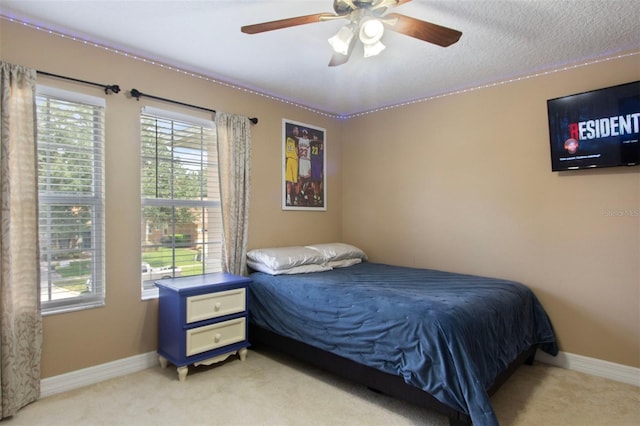 bedroom featuring ceiling fan, light colored carpet, and a textured ceiling