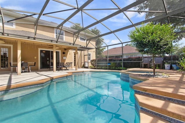 view of pool with an in ground hot tub, glass enclosure, ceiling fan, and a patio