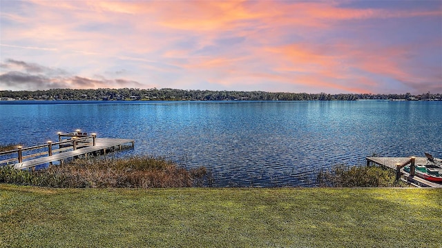 view of dock featuring a water view and a lawn