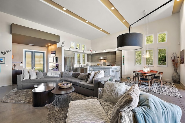 living room featuring french doors, a towering ceiling, and concrete flooring