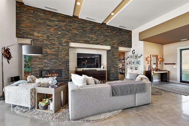 living room featuring concrete flooring and a stone fireplace