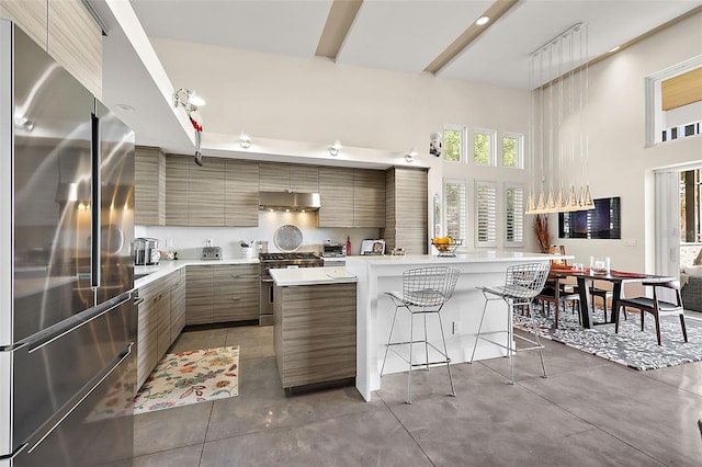 kitchen featuring a towering ceiling, a kitchen island, high quality appliances, a breakfast bar, and range hood