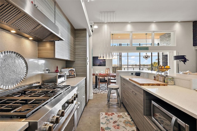 kitchen featuring a chandelier, decorative backsplash, wall chimney exhaust hood, and stainless steel appliances