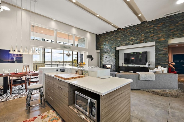 kitchen featuring concrete floors, a center island, a towering ceiling, and a fireplace