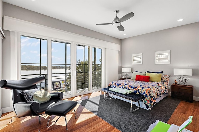 bedroom with ceiling fan, wood-type flooring, access to outside, and a water view