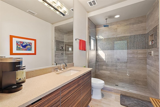 bathroom with toilet, vanity, tile patterned floors, and a shower with door