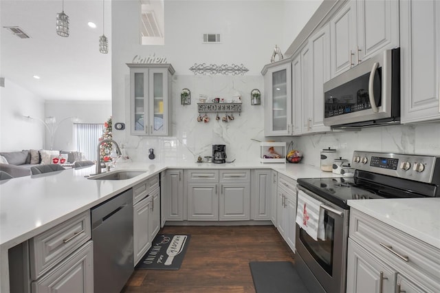 kitchen with gray cabinets, stainless steel appliances, tasteful backsplash, dark wood-type flooring, and sink