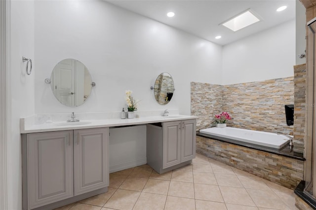 bathroom featuring tiled tub, tile patterned floors, vanity, and a skylight