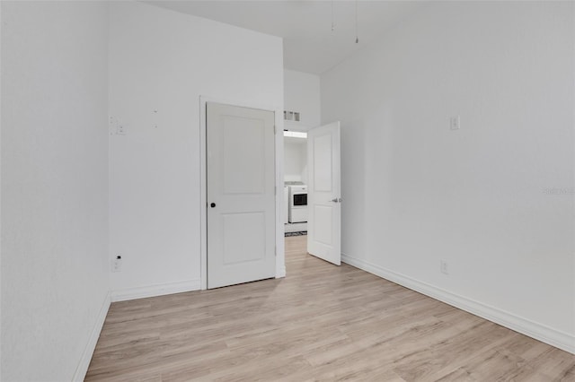 empty room with light hardwood / wood-style floors and washer / dryer