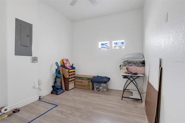 miscellaneous room with ceiling fan, electric panel, and light hardwood / wood-style flooring