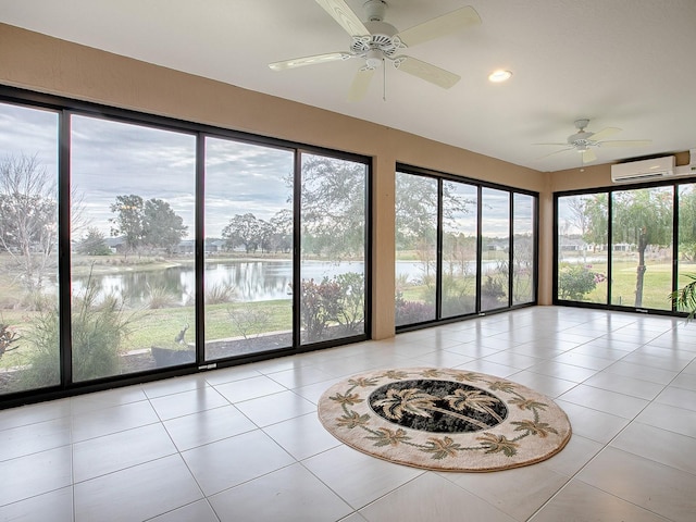 unfurnished sunroom with ceiling fan, a water view, and a wall mounted air conditioner