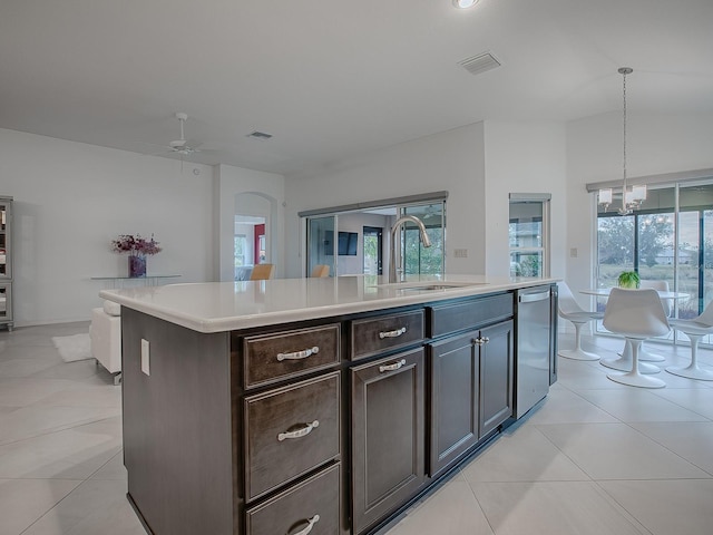 kitchen featuring sink, dark brown cabinetry, hanging light fixtures, a kitchen island with sink, and ceiling fan with notable chandelier