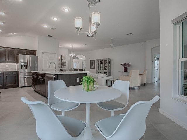 tiled dining space with vaulted ceiling, ceiling fan with notable chandelier, and sink