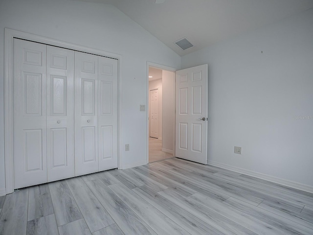 unfurnished bedroom with light hardwood / wood-style floors, a closet, and vaulted ceiling