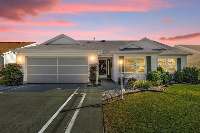 ranch-style home featuring a garage and a lawn