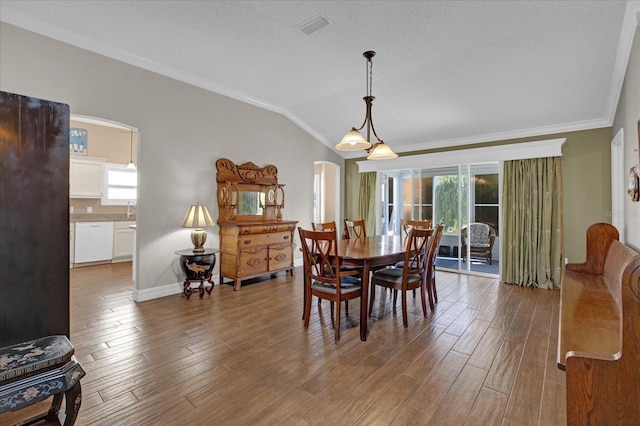 dining space with hardwood / wood-style floors, a textured ceiling, lofted ceiling, sink, and crown molding