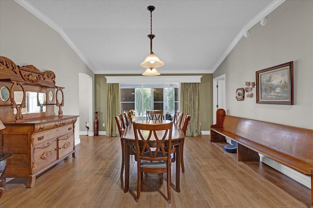 dining room featuring a textured ceiling, ornamental molding, and light hardwood / wood-style floors