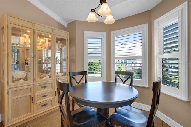 dining area with a textured ceiling, light hardwood / wood-style flooring, lofted ceiling, and an inviting chandelier