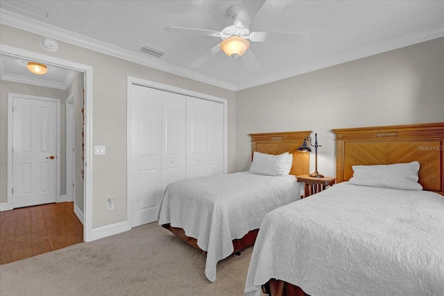 carpeted bedroom featuring a textured ceiling, ceiling fan, crown molding, and a closet