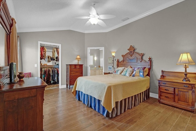 bedroom featuring ceiling fan, a walk in closet, a closet, and ornamental molding