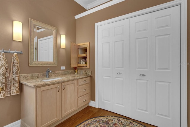 bathroom featuring vanity, wood-type flooring, and ornamental molding