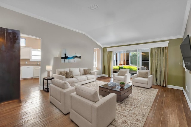 living room featuring hardwood / wood-style flooring, vaulted ceiling, ornamental molding, and sink