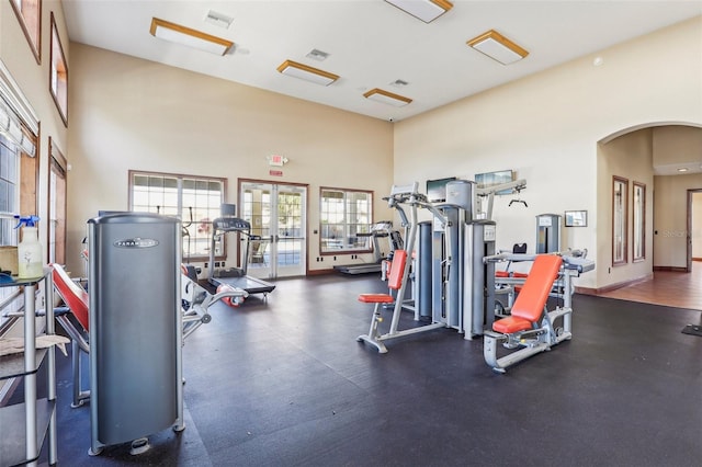 workout area featuring water heater, a towering ceiling, and french doors