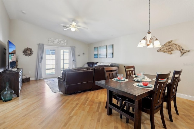 dining space featuring ceiling fan with notable chandelier, lofted ceiling, light hardwood / wood-style flooring, and french doors