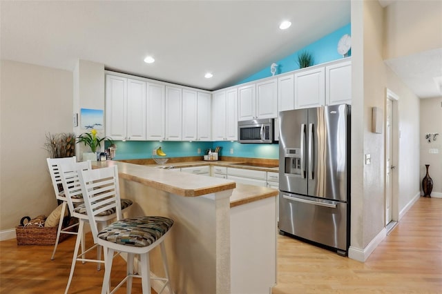 kitchen with stainless steel appliances, kitchen peninsula, and white cabinets