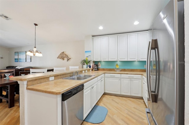 kitchen with pendant lighting, sink, stainless steel appliances, and kitchen peninsula