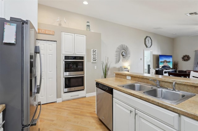 kitchen with white cabinetry, appliances with stainless steel finishes, sink, and light wood-type flooring