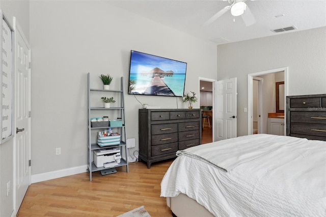 bedroom with ensuite bath, light hardwood / wood-style flooring, ceiling fan, and vaulted ceiling