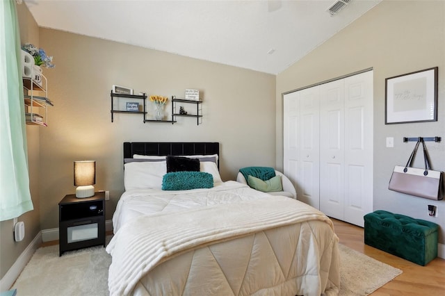 bedroom featuring lofted ceiling, light hardwood / wood-style floors, and a closet