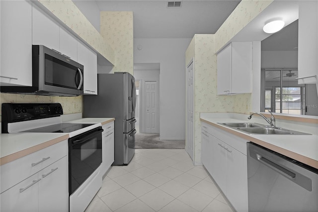 kitchen with white cabinetry, sink, light carpet, and stainless steel appliances