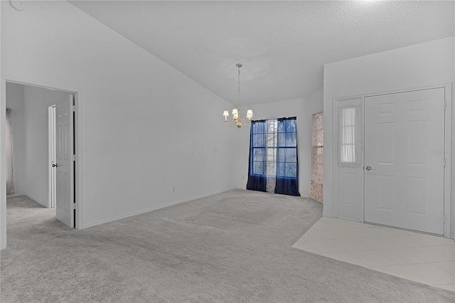 foyer with lofted ceiling, light colored carpet, a notable chandelier, and a textured ceiling