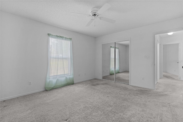 unfurnished bedroom with ceiling fan, light colored carpet, a closet, and a textured ceiling