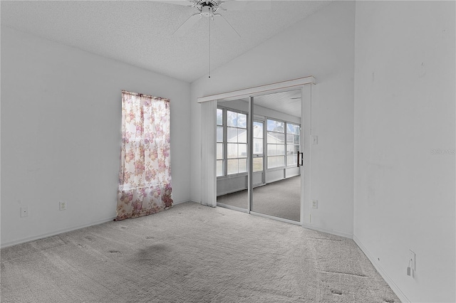 empty room with ceiling fan, lofted ceiling, light carpet, and a textured ceiling