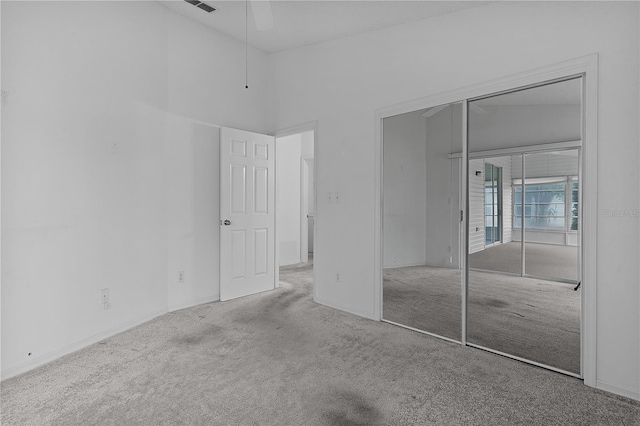 unfurnished bedroom featuring vaulted ceiling, light colored carpet, ceiling fan, and a closet