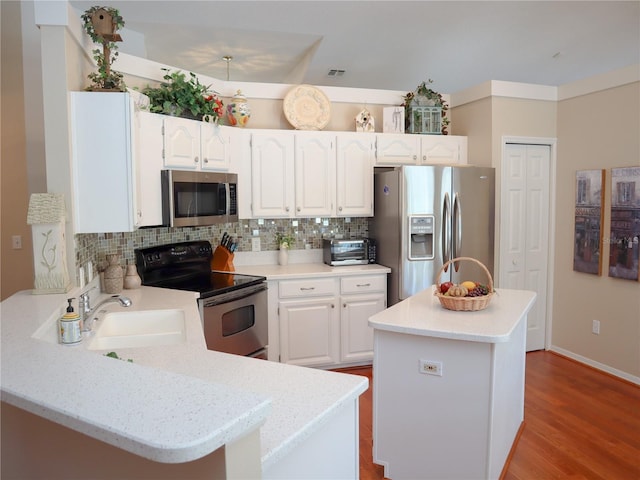 kitchen featuring appliances with stainless steel finishes, white cabinetry, a sink, and backsplash