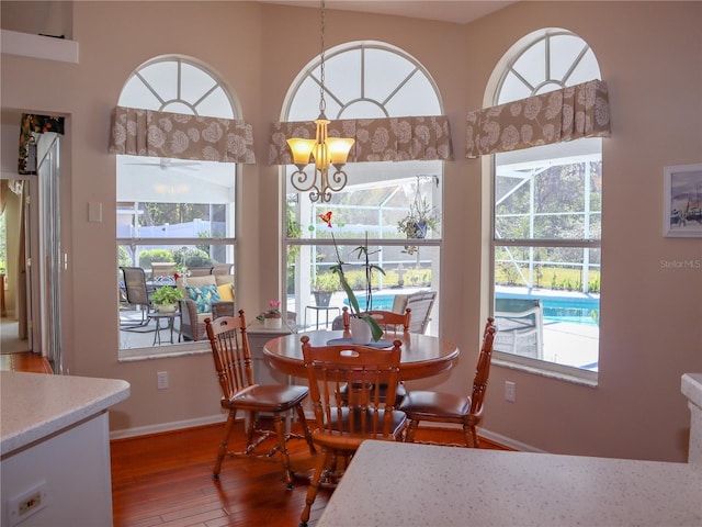 dining area featuring a chandelier, plenty of natural light, baseboards, and hardwood / wood-style flooring