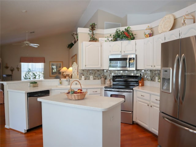 kitchen featuring stainless steel appliances, a peninsula, white cabinetry, vaulted ceiling, and light countertops