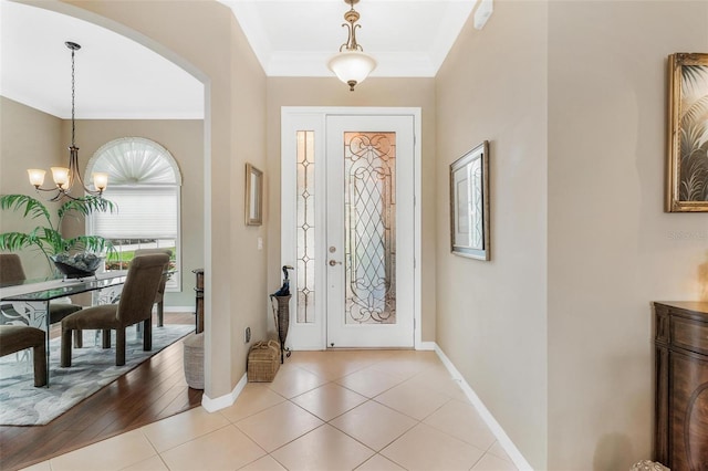 entrance foyer featuring light tile patterned floors, a notable chandelier, and ornamental molding