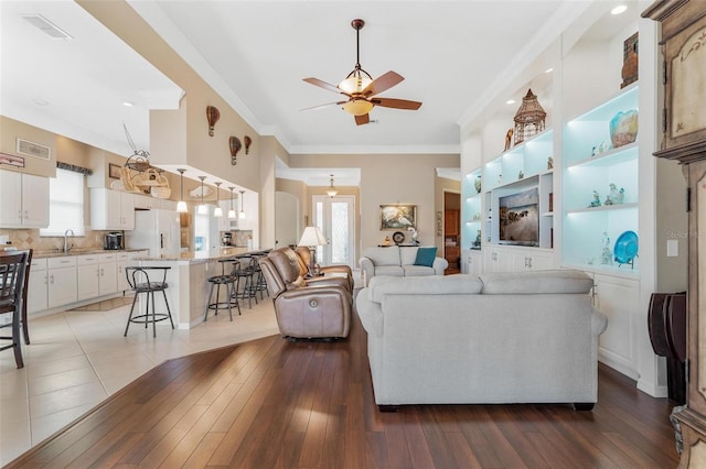 living room featuring hardwood / wood-style flooring, ornamental molding, sink, and ceiling fan