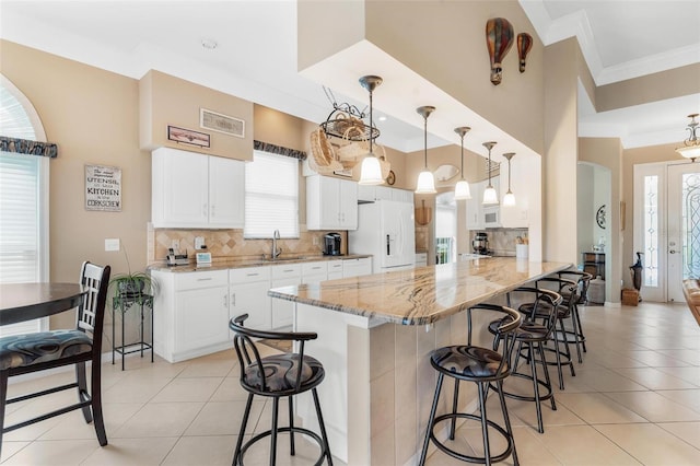 kitchen with white cabinetry, tasteful backsplash, hanging light fixtures, kitchen peninsula, and white appliances