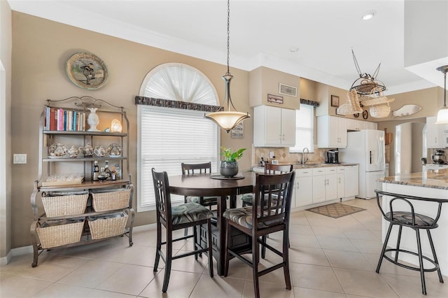 dining room with light tile patterned floors, crown molding, and sink