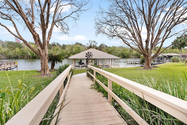 dock area with a gazebo, a water view, and a yard