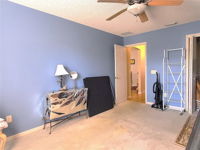 interior space with ceiling fan, carpet floors, and a textured ceiling