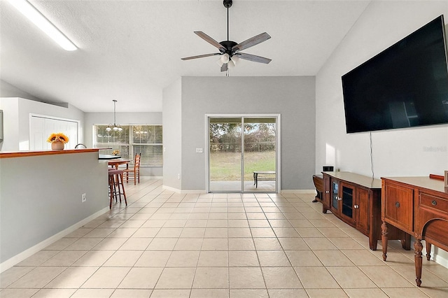 living room with ceiling fan with notable chandelier, light tile patterned floors, and lofted ceiling